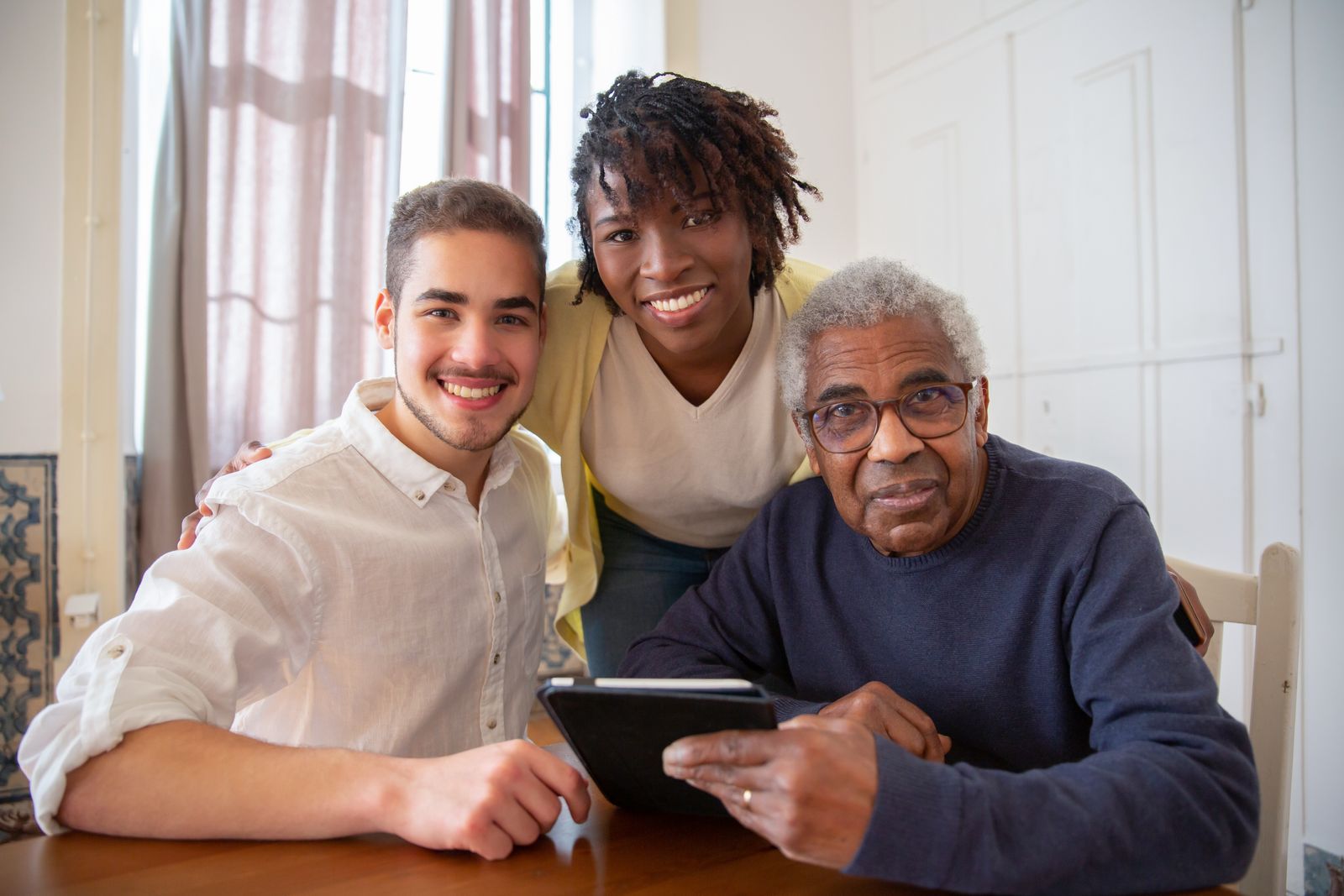 Three people of different generations smiling together at a kitchen table