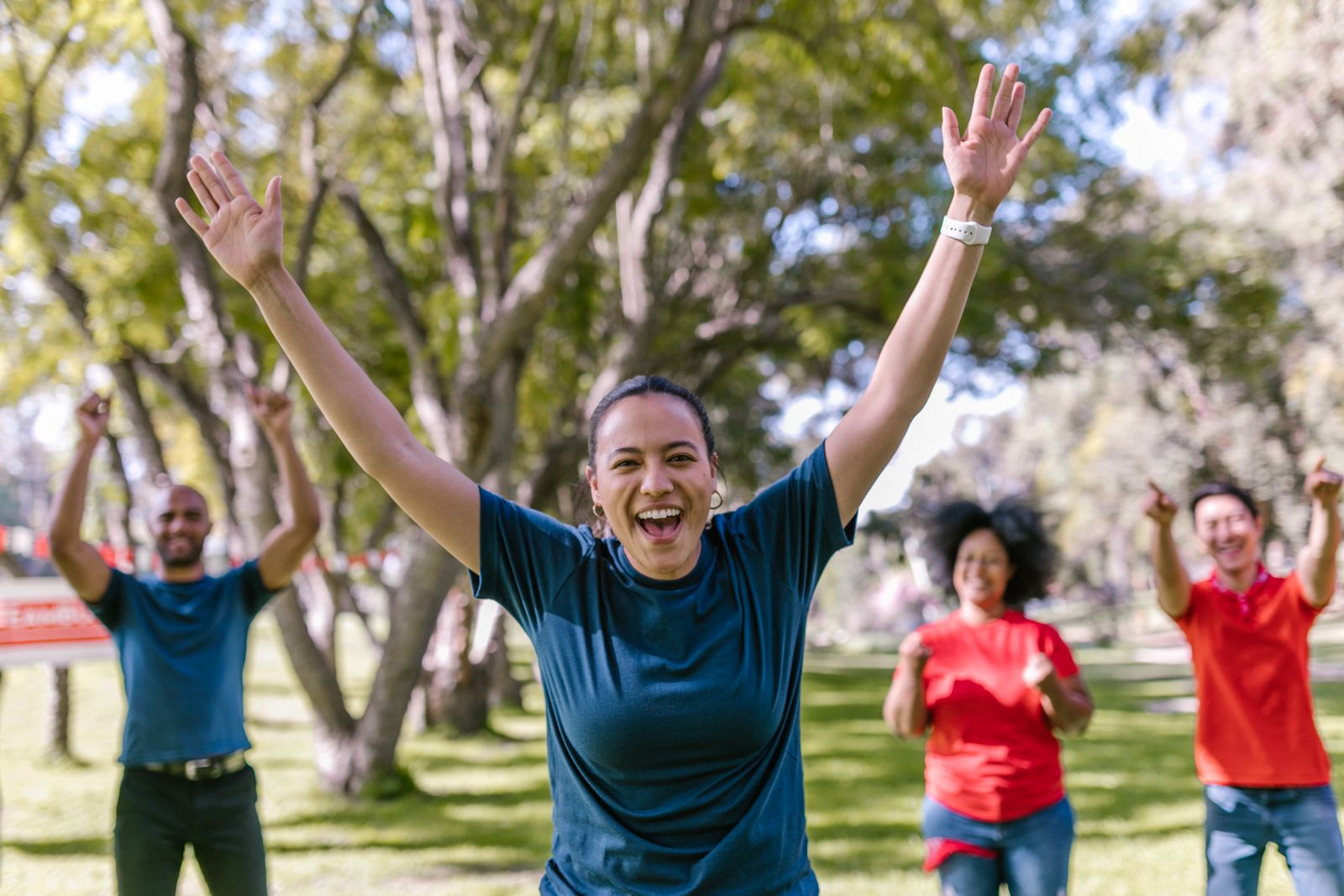 A diverse group of people smiling and celebrating together outdoors