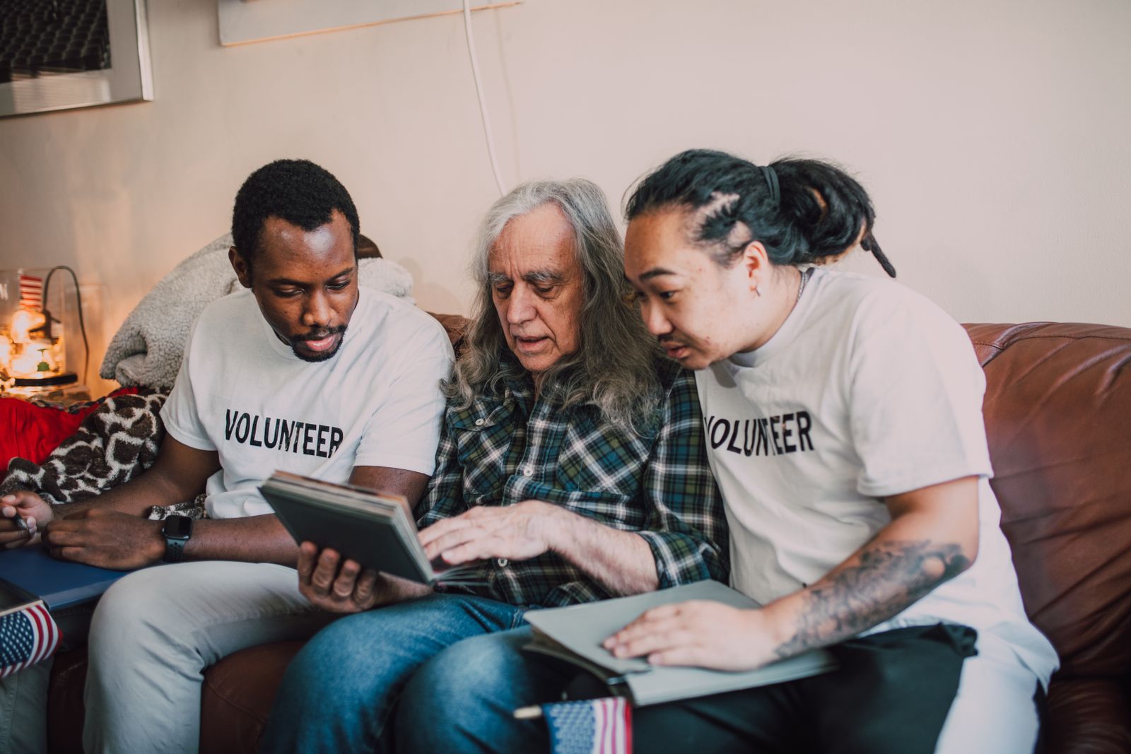 Volunteers sitting with an older adult at home during a friendly visit